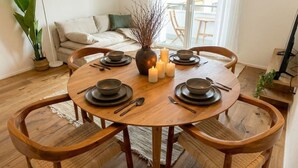 A round wooden dining table with six chairs, candles, and dinnerware set for six. - Riverfront Apt | Balcony | Zurich Airport | WiFi (Opfikon)