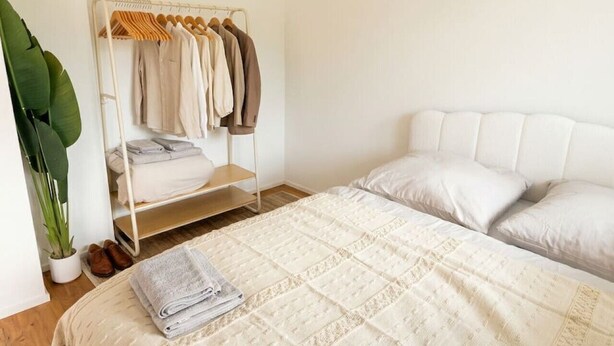A bedroom with a bed, a wardrobe, and a potted plant. - Riverfront Apt | Balcony | Zurich Airport | WiFi (Opfikon)