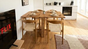 Eine moderne Küche mit weißen Schränken, einem Holzespeisesaal mit vier Stühlen und einer Pendelleuchte.