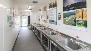 A clean, well-lit public restroom with multiple sinks and hand dryers, and informational posters on the walls. - Sherwood Pines - Deluxe Pod 3 (Mansfield)