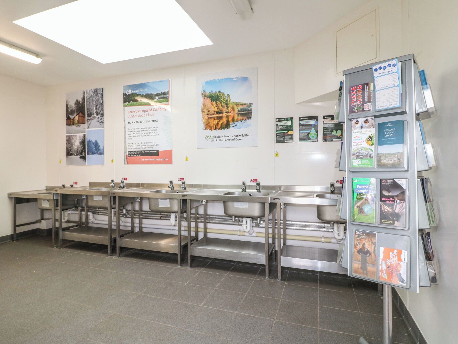 A public restroom with multiple sinks, a handwashing station, and informational posters on the walls.