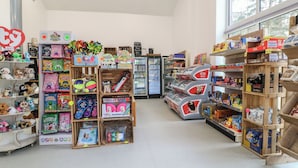 A toy store with shelves stocked with toys, a refrigerator, and a window with a view. - Sherwood Pines - Deluxe Pod 3 (Mansfield)