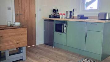 A compact kitchen with a microwave, kettle, and a small refrigerator.
