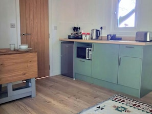 Una cocina compacta con microondas, hervidor y un refrigerador pequeño.