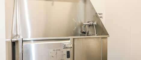 A stainless steel commercial kitchen sink with a control panel and a faucet.