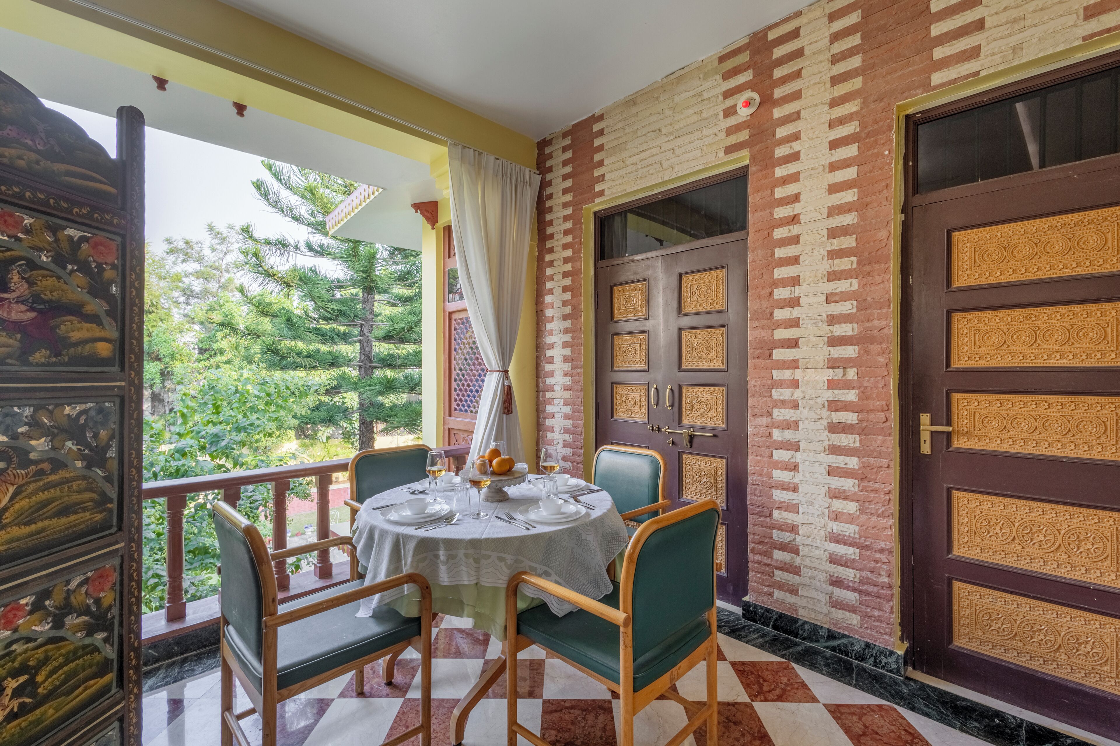 A dining area with a round table, chairs, and a view of greenery outside.