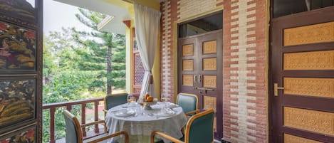 Un espace repas avec une table ronde, des chaises et une vue sur la verdure environnante.
