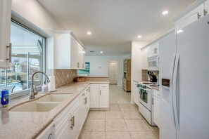 Una cocina moderna con armarios blancos, un lavamanos doble, una estufa y un refrigerador.