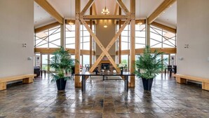 A spacious lobby with high ceilings, wooden beams, large windows, and potted plants. - Bright 1 Bdrm at Amenity Rich Resort 102 (West Kelowna)