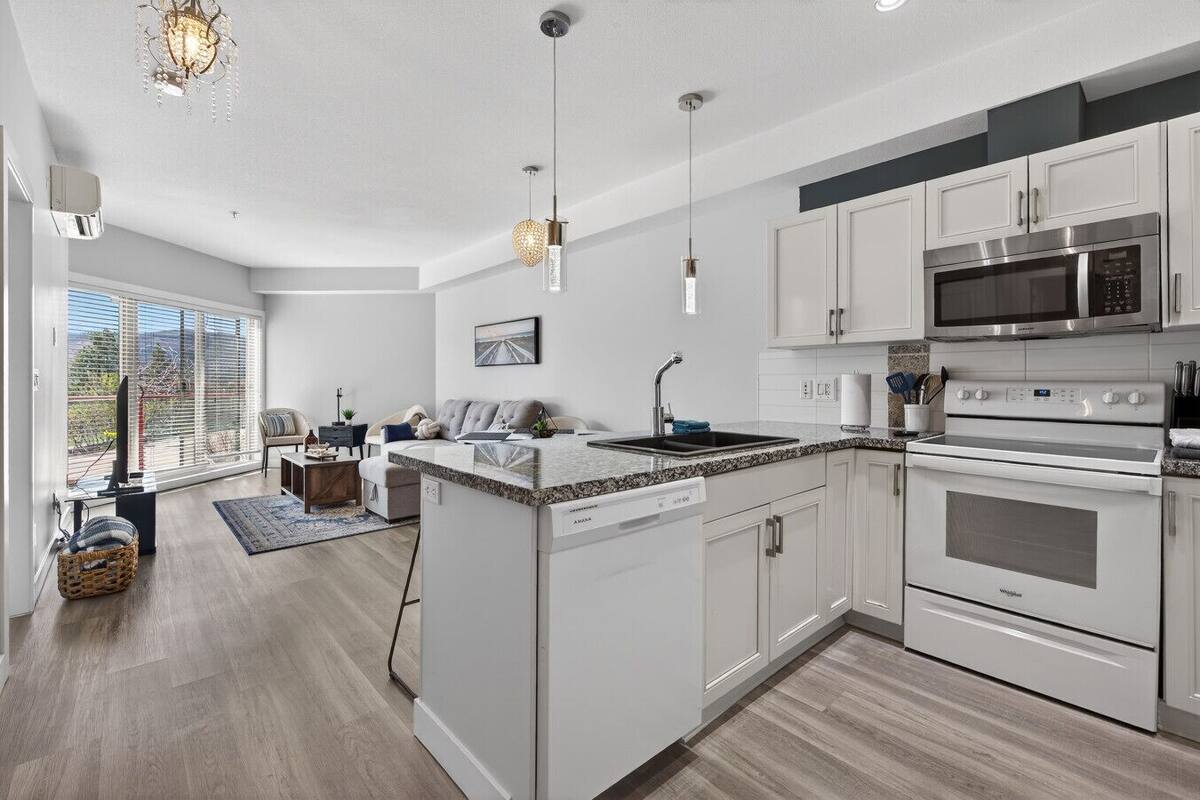 A modern kitchen with a dishwasher, oven, microwave, and granite countertop.