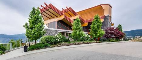 A modern house with a sloped roof, stone foundation, and a paved driveway.