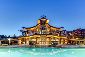 Un edificio de varios pisos con una piscina al frente.