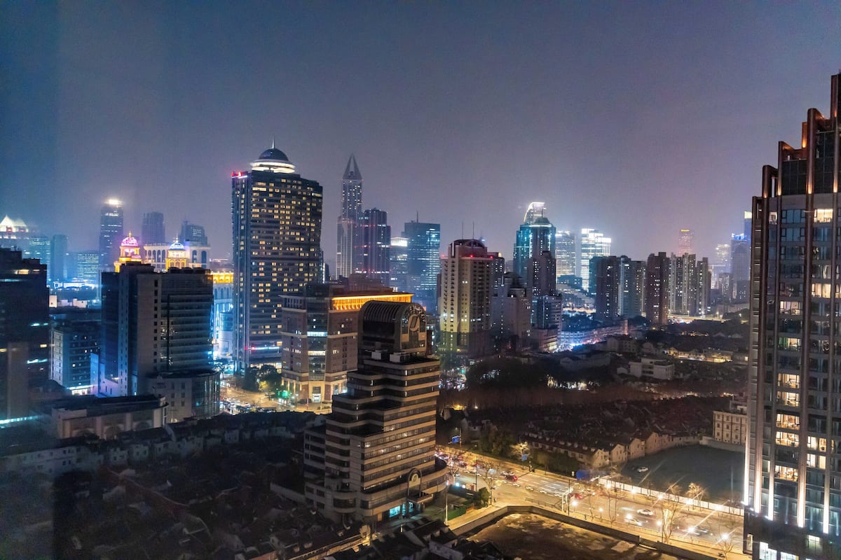 A nighttime cityscape with high-rise buildings, illuminated windows, and a clear view of the urban environment.