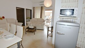 Un espace de vie compact comprenant un coin repas, un canapé, une petite table et un four à micro-ondes.