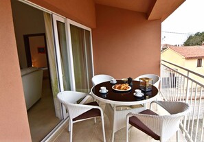 A balcony with a round table, white wicker chairs, and a dining setup with croissants and coffee cups. - Ideal getaway flat with pool and rumpus room (Tar)