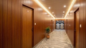 Un pasillo con paneles de madera, una planta en maceta y piso de mármol.