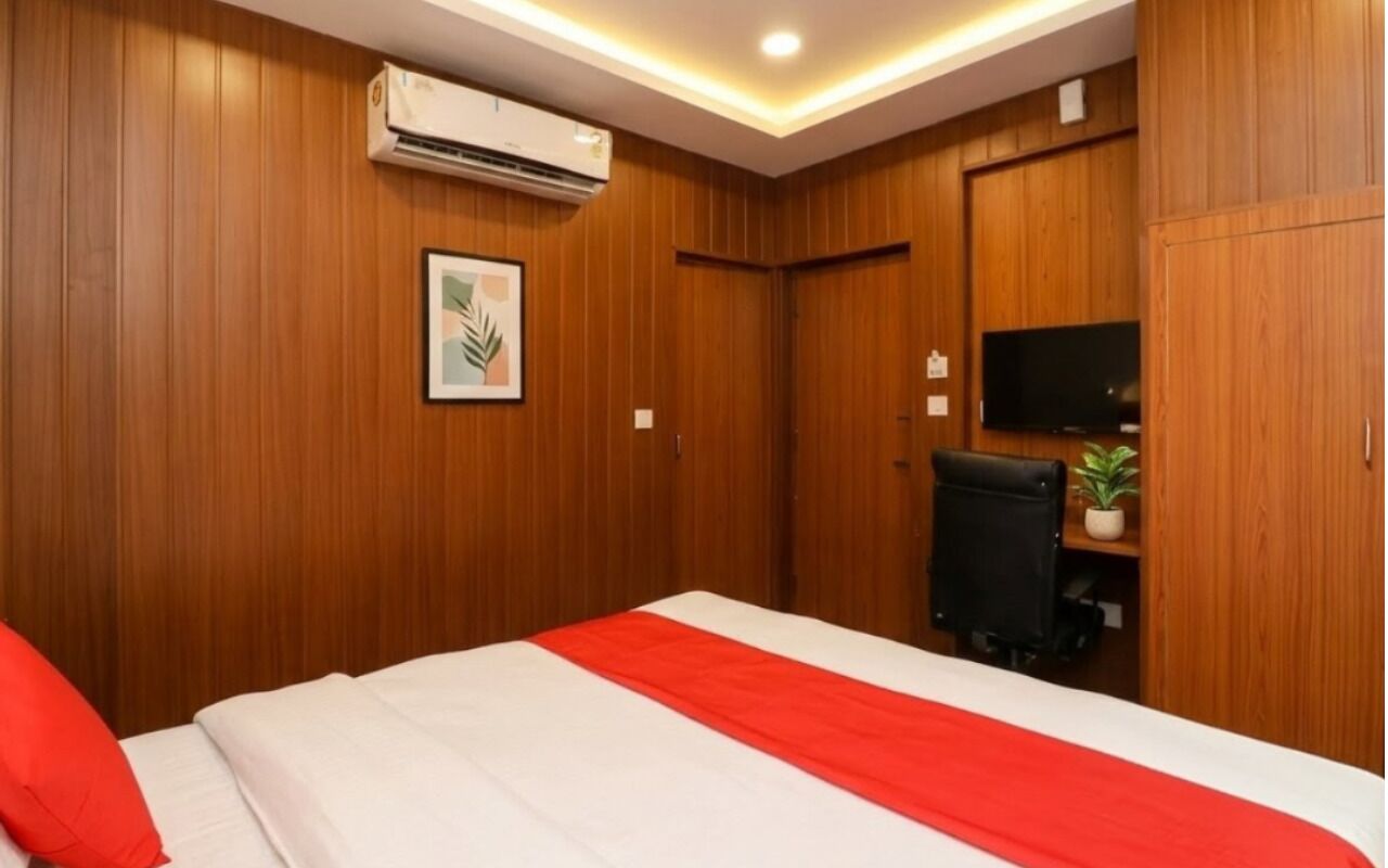 Una habitación de hotel con cama, aire acondicionado, televisor y escritorio con silla.
