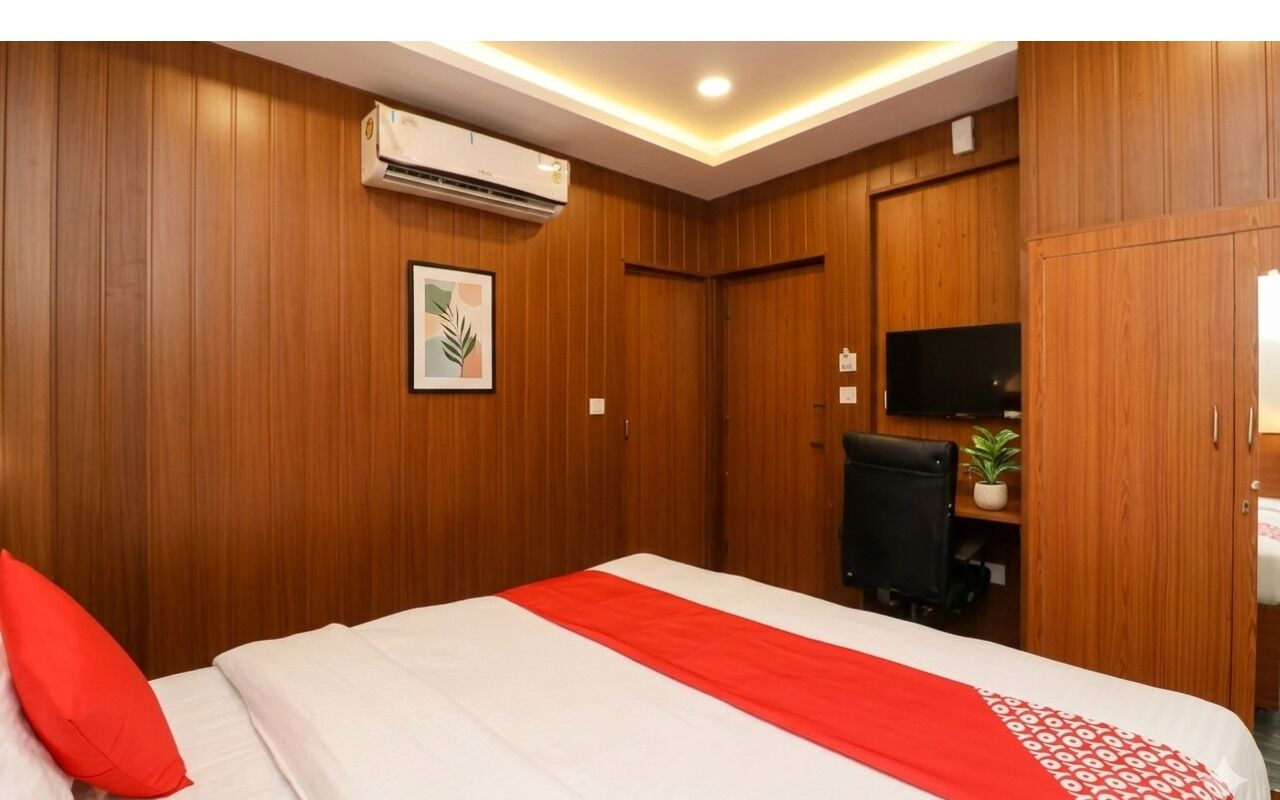 A hotel room with a bed, a desk, a chair, a television, and a wardrobe.