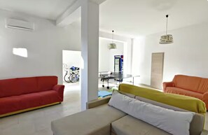Un salon moderne avec un canapé rouge, un canapé beige et un plaid jaune.
