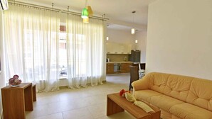 A living room with a sofa, a wooden coffee table, and a kitchen in the background. - Perfect holiday apartment with pool (Tar)