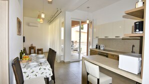 A compact kitchen with a dining area, featuring a table set for four, a coffee machine, and a refrigerator. - Perfect holiday apartment with pool (Tar)