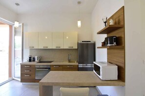 Une cuisine moderne dotée d’un four, d’un micro-ondes et d’un réfrigérateur encastrés, de meubles de rangement en bois et d’un petit coin repas.