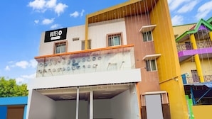 A hotel with a signboard, a covered parking area, and a multi-story building with balconies. - Super Hotel O Aarapalayam (Madurai)