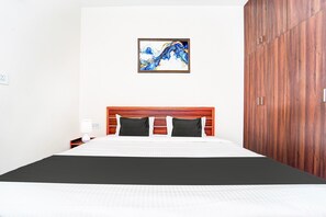 Un lit bien fait, avec une tête de lit en bois, une table de chevet avec une lampe et une armoire avec un miroir.