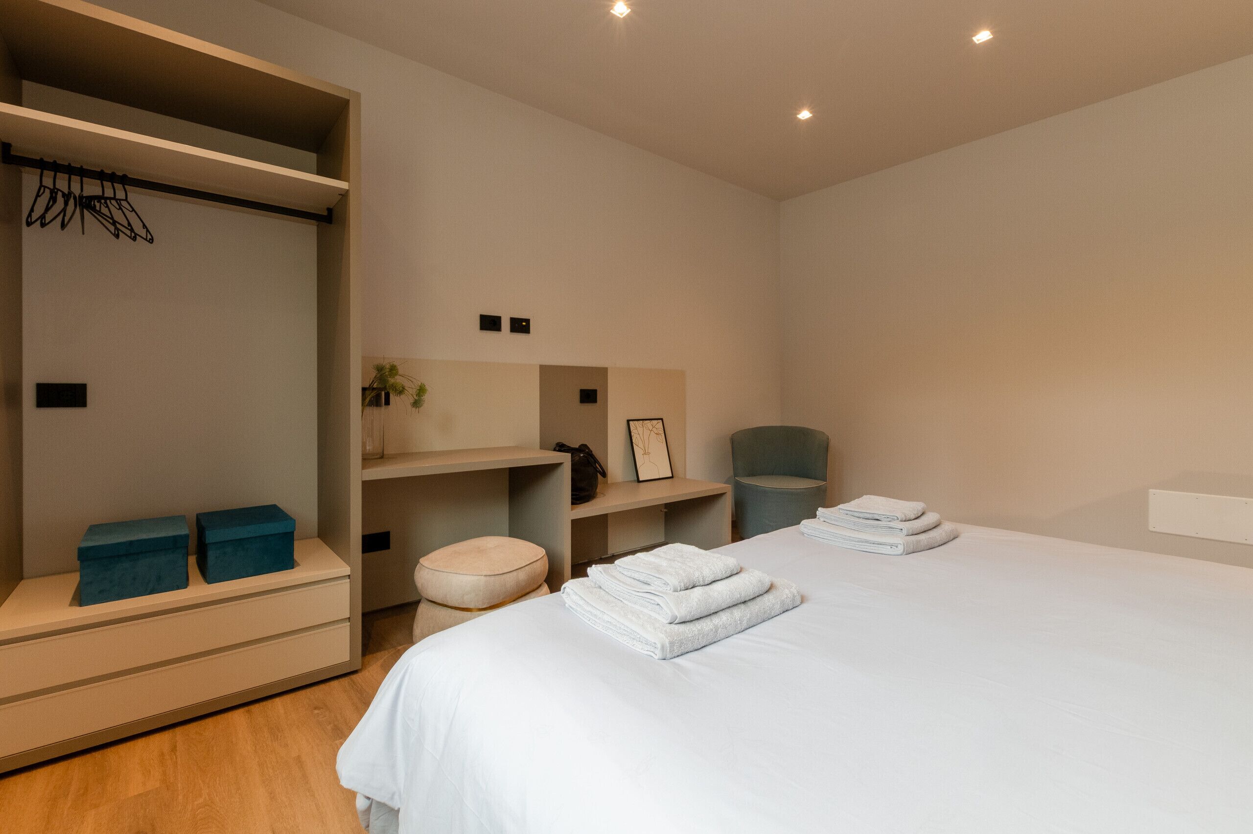 Une chambre d’hôtel moderne dotée d’un grand lit, d’une armoire, d’un petit coin salon et d’un bureau.