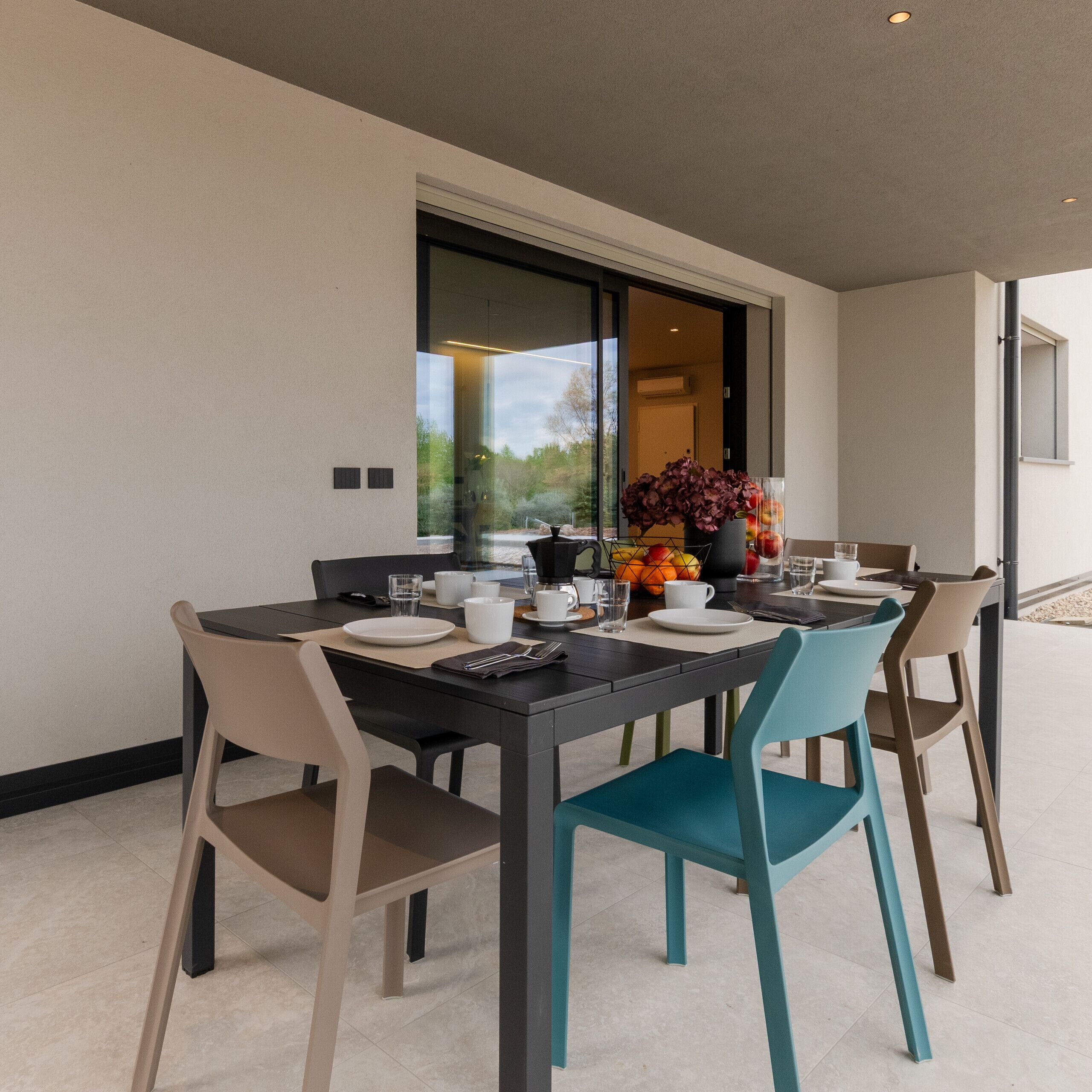 A modern dining area with a table set for four, chairs, and a vase of flowers.