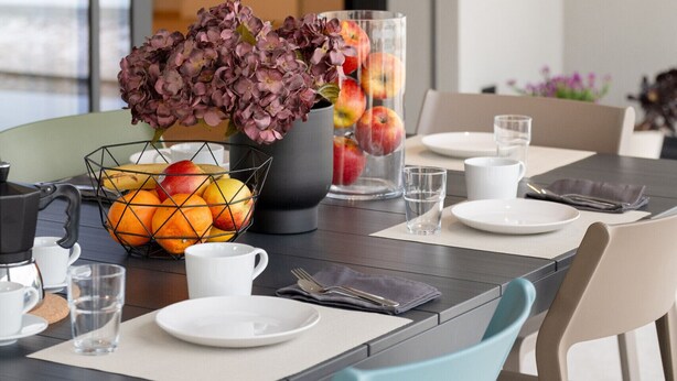 A dining table set with plates, glasses, and a fruit bowl. - Villa Aqua_Giuly Suite Apartment_Lake View & Pool (San Felice del Benaco)