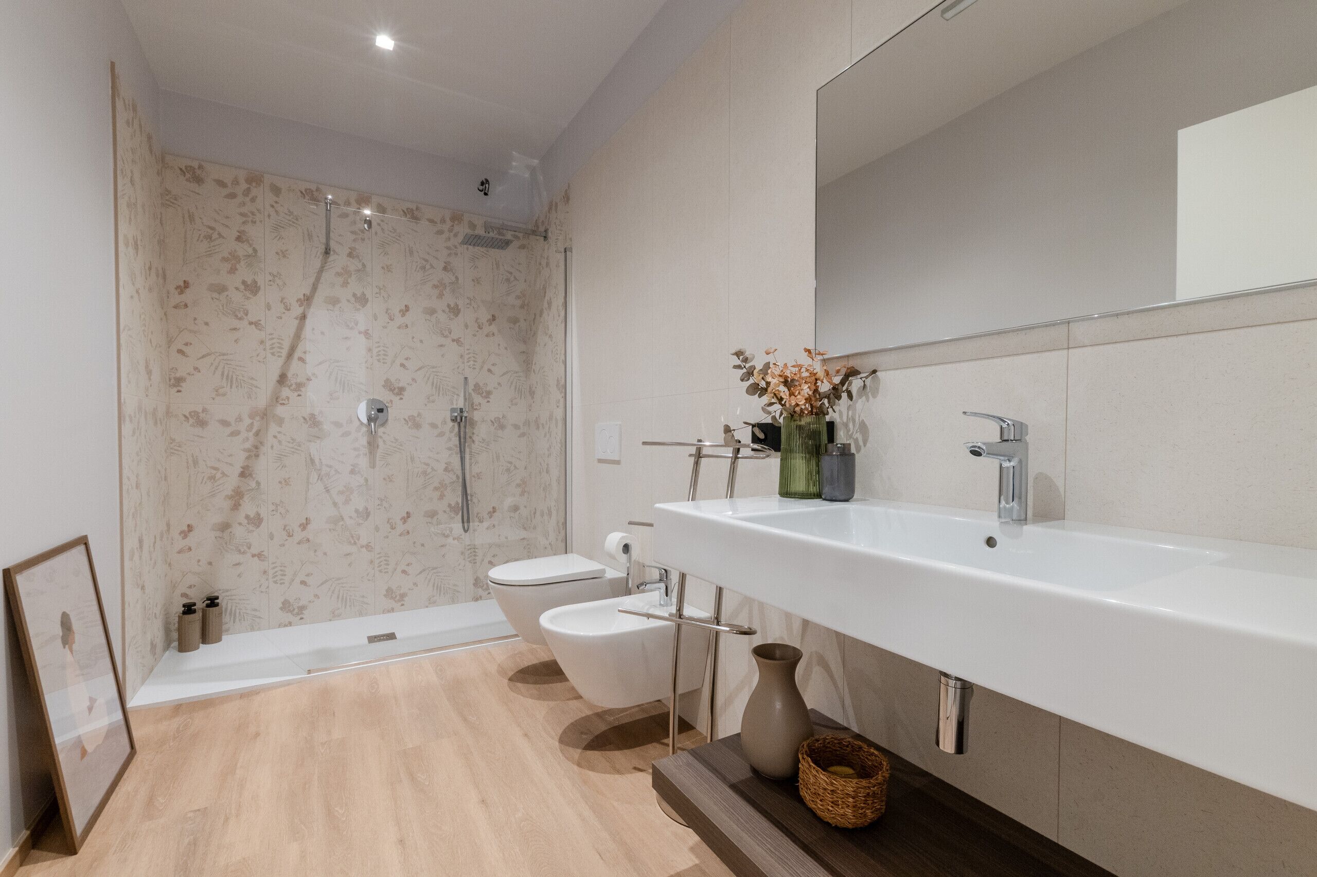 Un bagno moderno con doccia, toilette, bidet e uno specchio grande.
