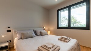 A modern bedroom with a large bed, bedside lamps, a window with a view, and neatly folded towels. - Villa Aqua_Lydia Suite Apartment_Lake View & Pool (San Felice del Benaco)