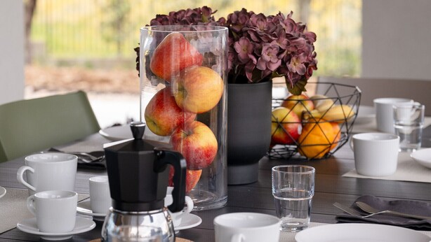 A breakfast table with a coffee maker, fruit, and flowers. - Villa Aqua_Lydia Suite Apartment_Lake View & Pool (San Felice del Benaco)