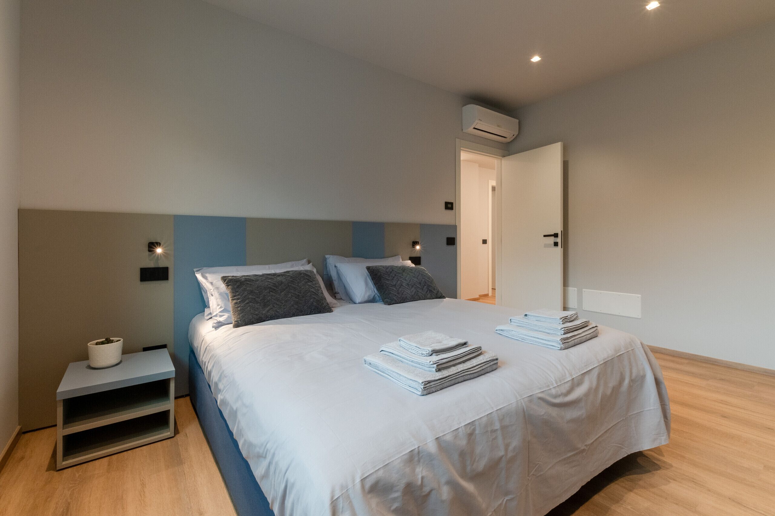 Quarto com cama, mesas de cabeceira e ar condicionado.