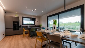 A modern kitchen with a dining area, large windows, and a view of greenery. - Villa Aqua_Lydia Suite Apartment_Lake View & Pool (San Felice del Benaco)