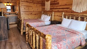 Una habitación de cabaña de madera con dos camas, un cabecero de madera y una pequeña cocina.
