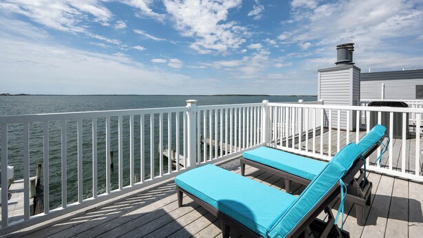 A deck with two lounge chairs, a white railing, and a view of the water. - Three Bedroom Two Bath Townhome Directly On The Bay (Ocean City)