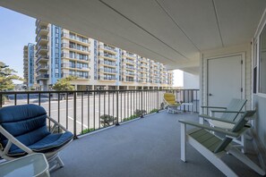Ein Balkon mit Blick auf ein mehrstöckiges Gebäude, ein Stuhl, ein Tisch und eine Tür.