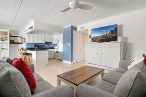 Ein modernes Wohnzimmer mit grauem Sofa, einem Holztisch und einem Fernseher auf einer Kommode.