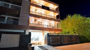 A multi-story building with balconies, a visible entrance, and a sign indicating a restaurant. - SnapStayz (Noida)