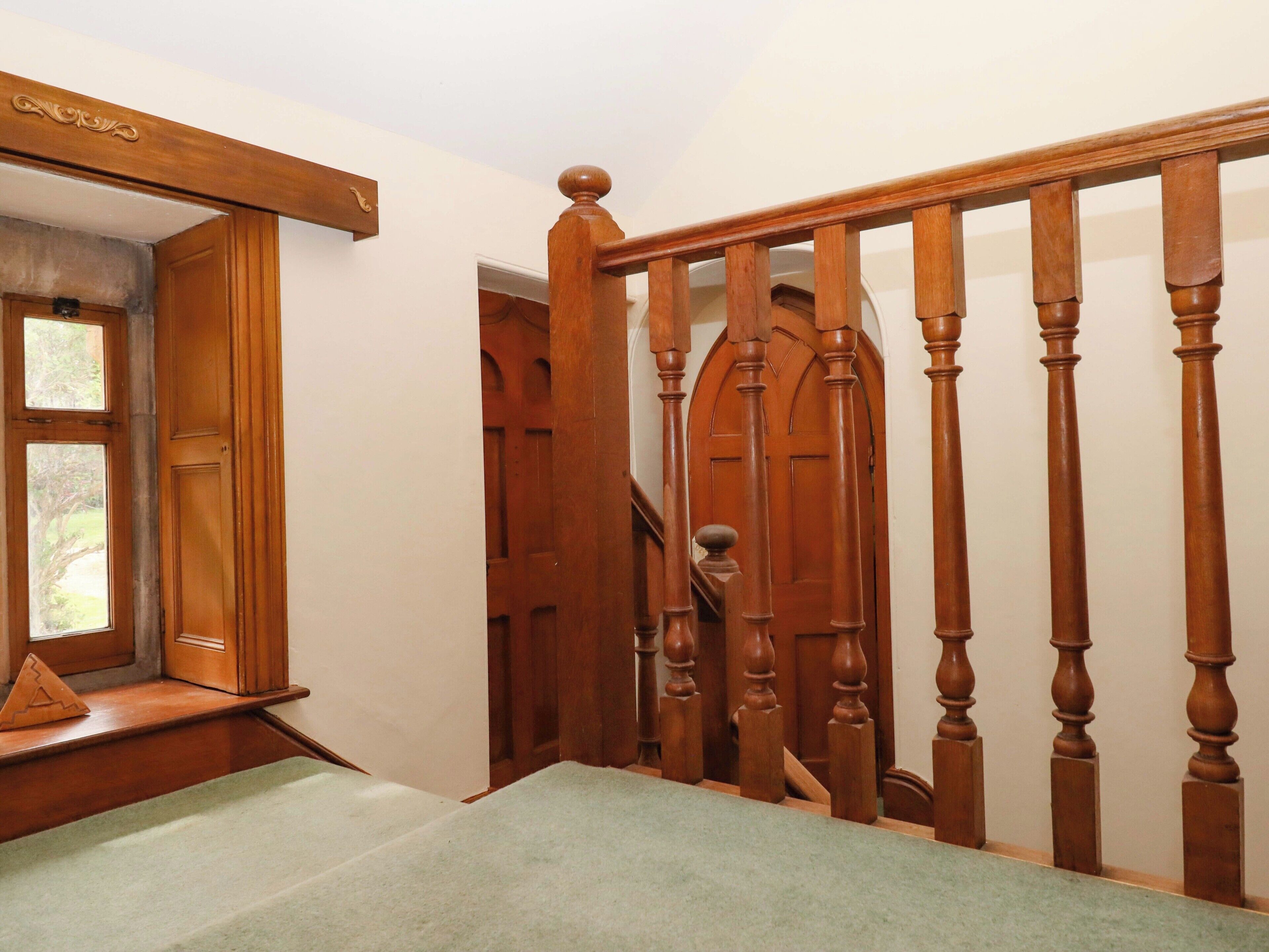 A wooden staircase with a handrail, a door with a window, and a carpeted landing.