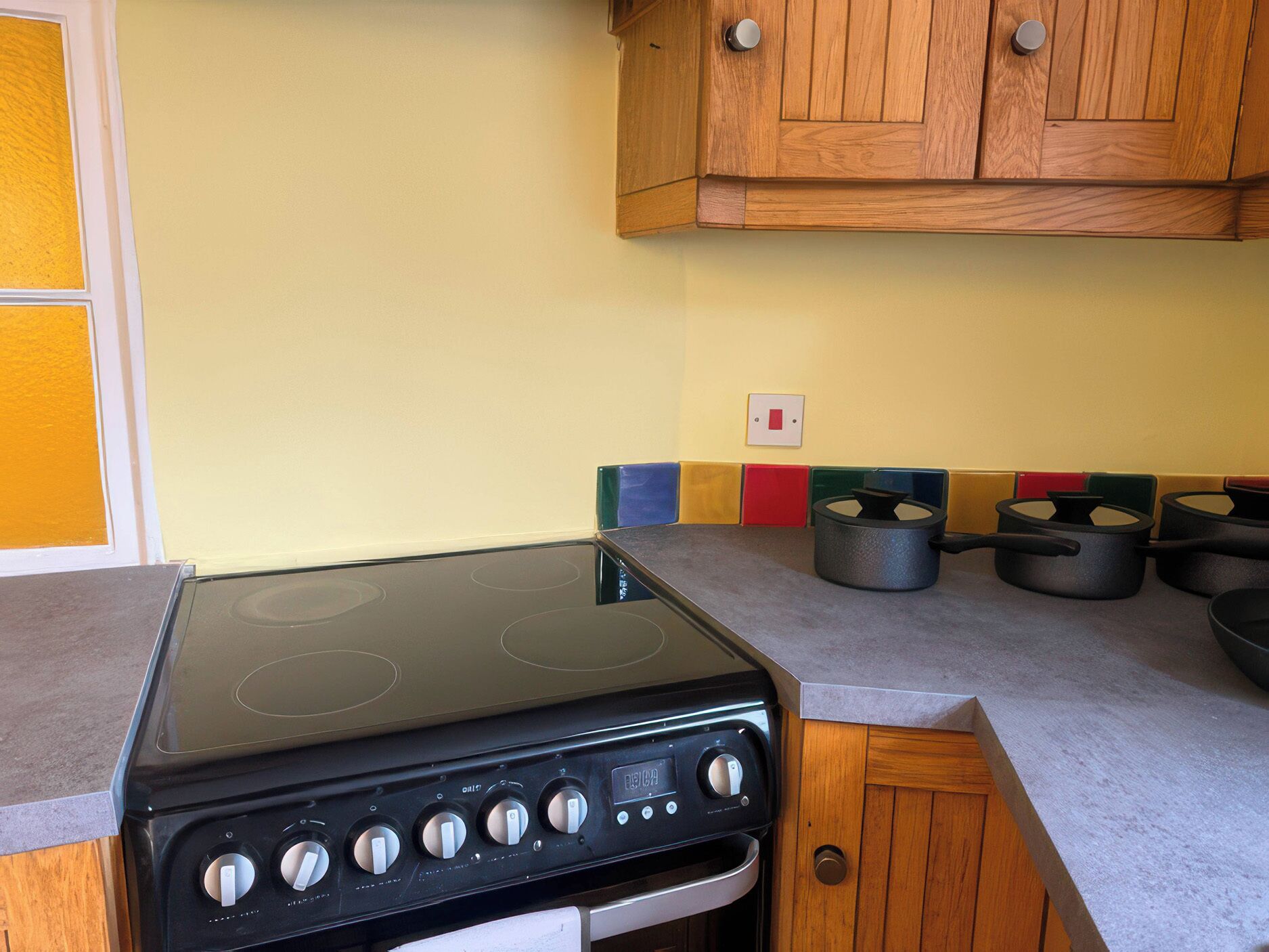 Una cocina con estufa negra, armarios de madera y salpicadero colorido.