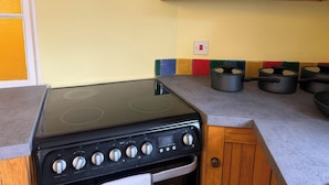 Une cuisine avec un poêle noir, des armoires en bois et un crédence aux couleurs vives.