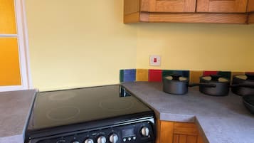 Una cocina con estufa negra, armarios de madera y salpicadero colorido.