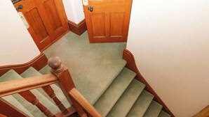 Un escalier en bois, dont les marches sont recouvertes de moquette, mène à une porte.