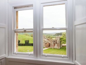 Una ventana con vistas a un edificio de piedra y paisaje verde.