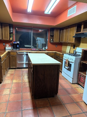 A kitchen with wooden cabinets, a stainless steel refrigerator, a white countertop, a stove, and a window with a view. - Desert Sunset Escape-Private, Peaceful & Relaxing (El Paso)