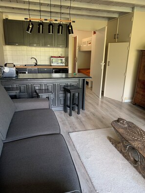 A modern kitchen with dark cabinetry, a central island, and pendant lighting. - Studio 4/5 persons Le Chambeyron Pra Loup (Uvernet-Fours)