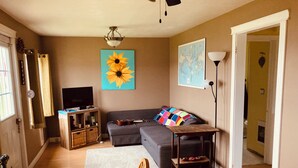 Una sala de estar con un sofá, una mesa de centro, un televisor y una estantería.